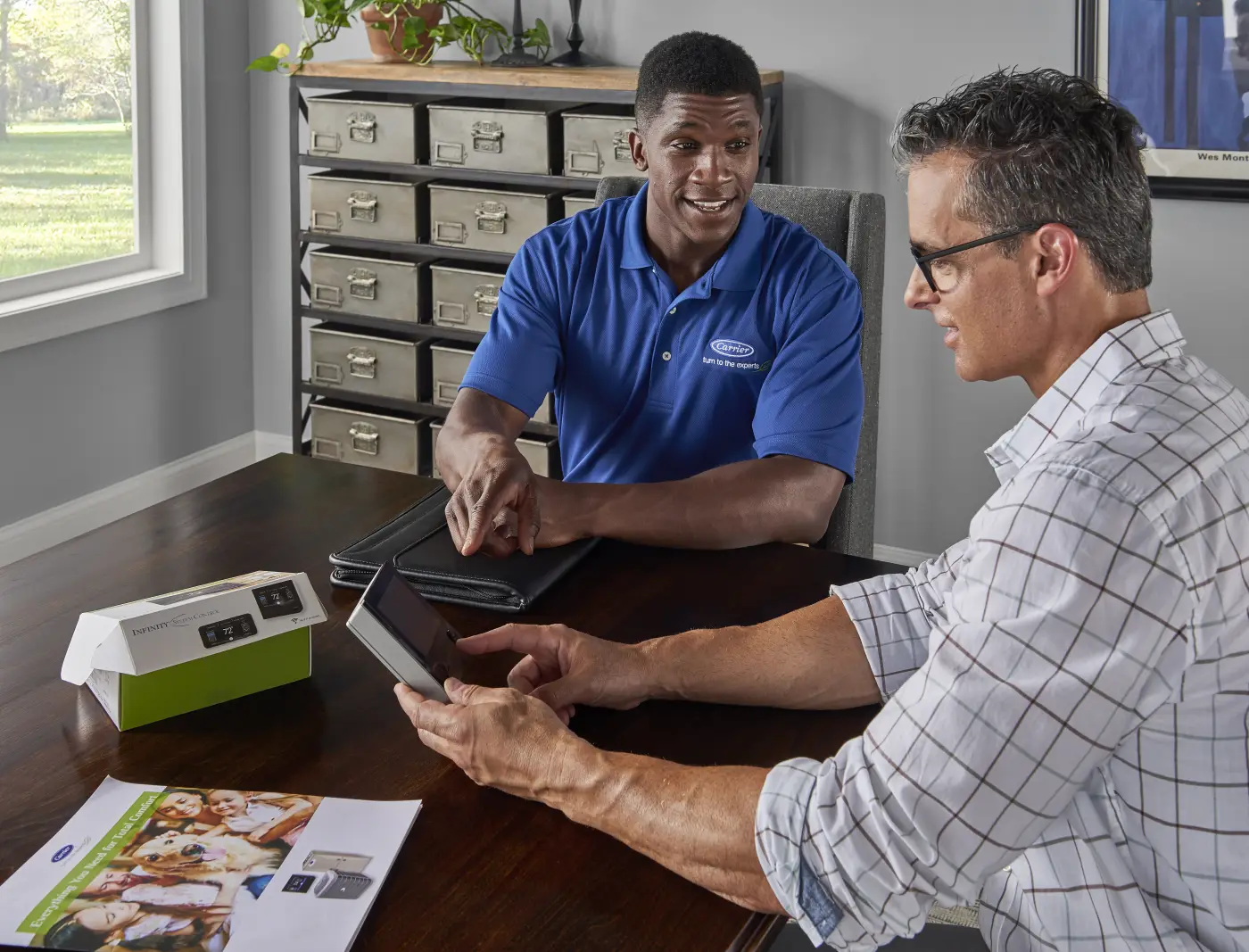 A Carrier dealer reviewing system options with a homeowner at a kitchen table