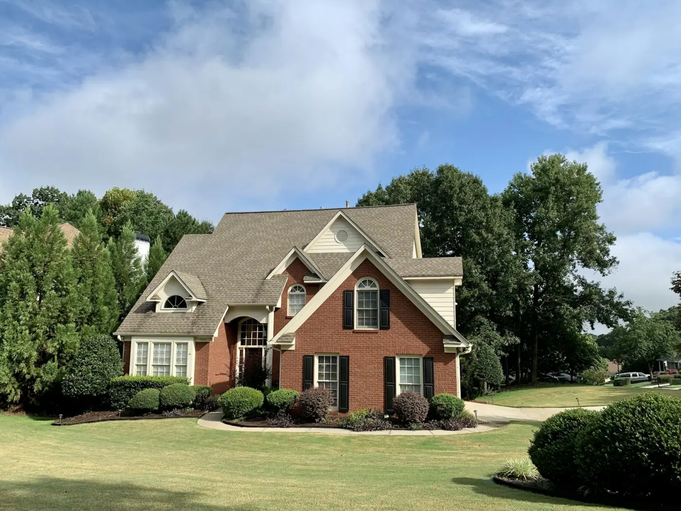 Brick suburban home under a wide blue sky