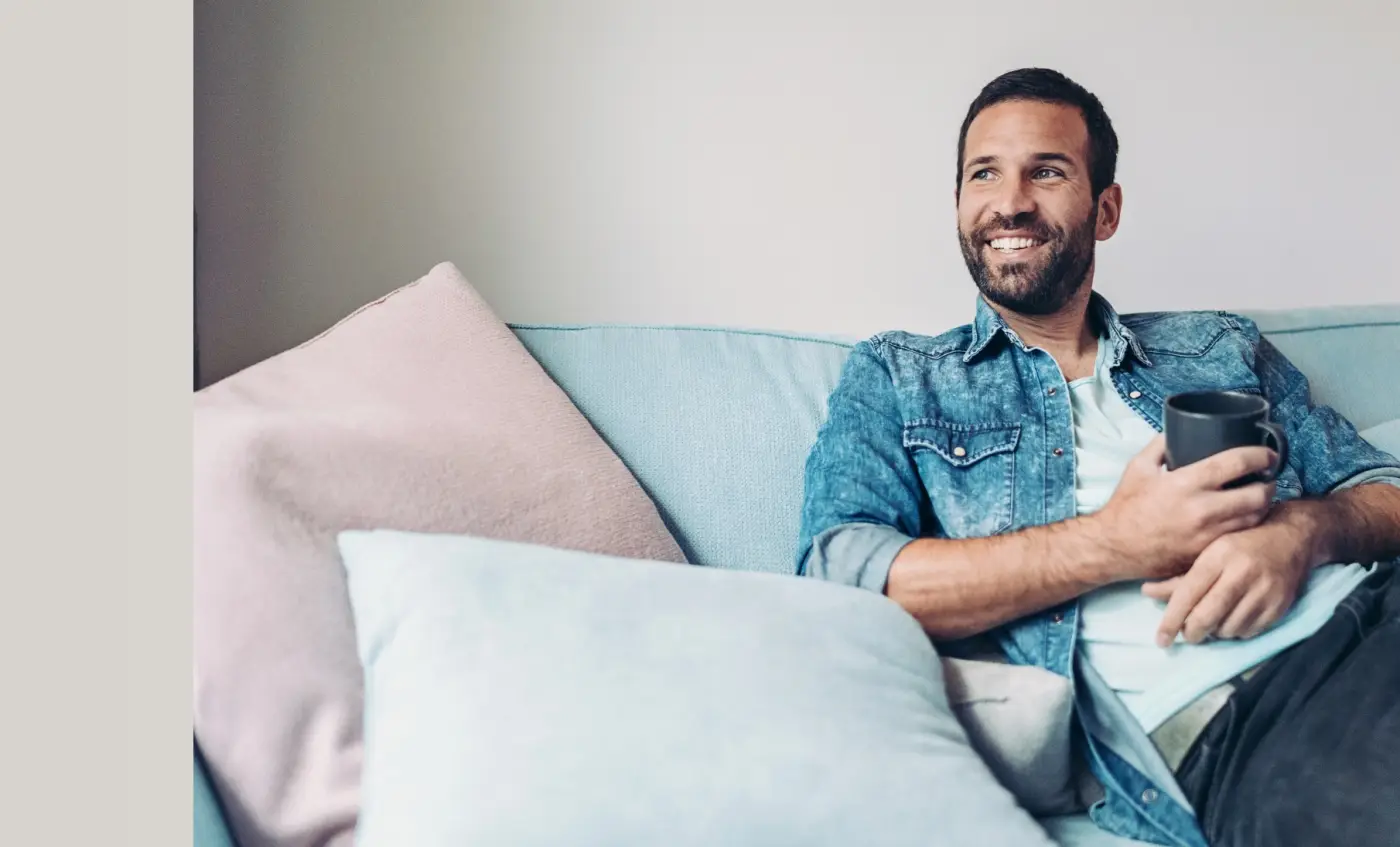 Man relaxing on a sofa at home with a mug of coffee