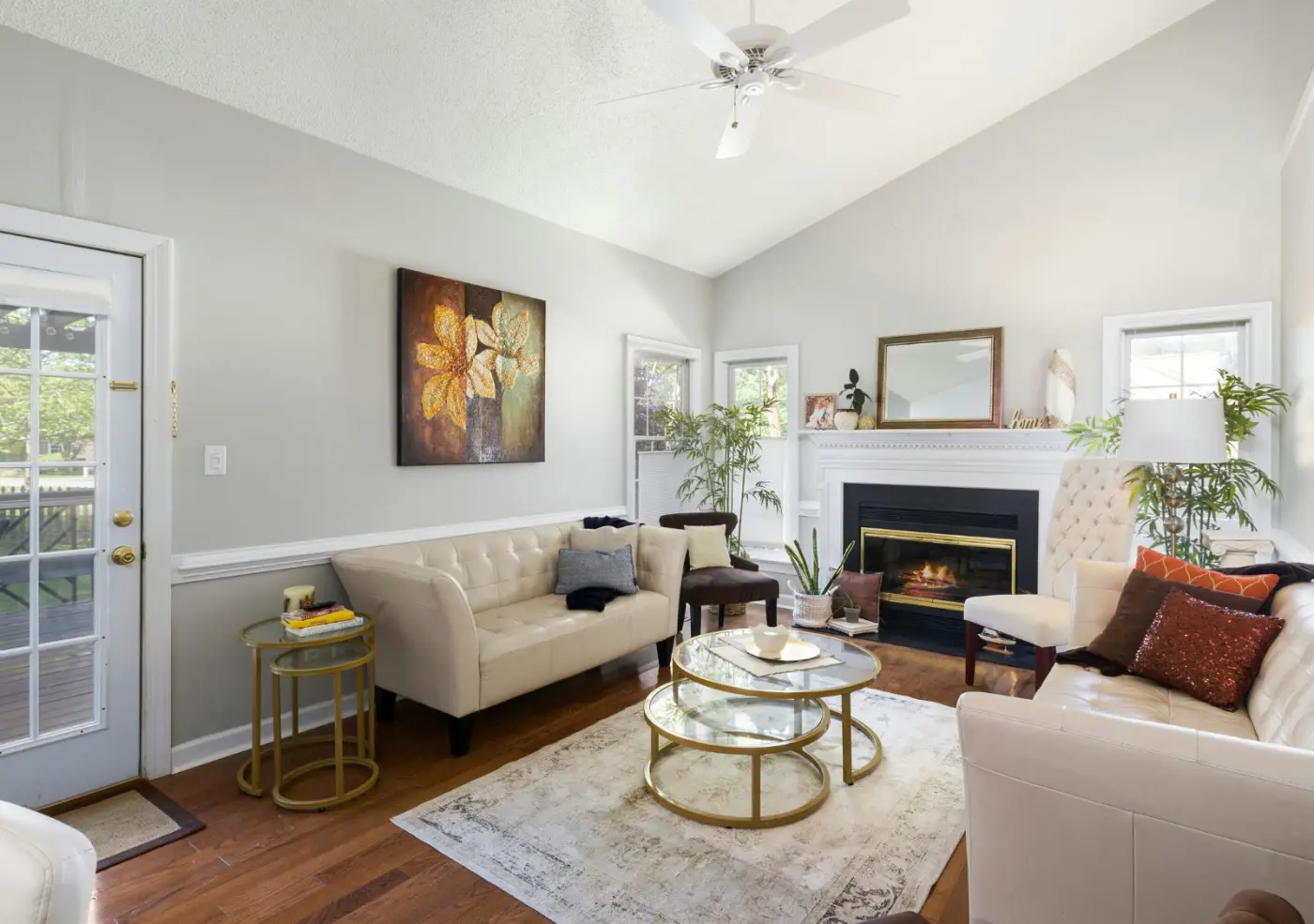 Living room with a vaulted ceiling, ceiling fan and a lit fireplace